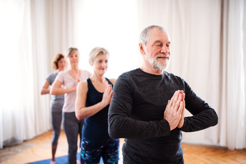 Group of senior people doing yoga exercise in community center club.