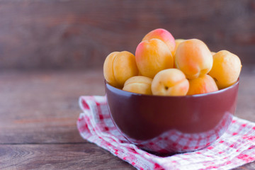 ripe fresh apricots in a bowl on a wooden table