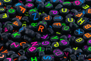 black plastic beads with colored letters placed randomly