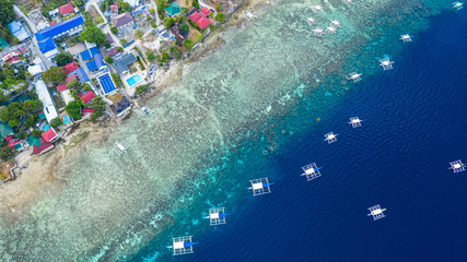 Aerial view of Filipino boats floating on top of clear blue waters, Moalboal is a deep clean blue ocean and has many local Filipino boats in the sea. Moalboal, Cebu, Philippines.
