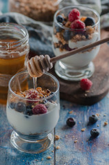 yogurt with granola and raspberries black chorynitsa and honey. yogurt in the blue on the table	