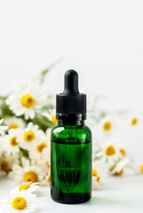 Essential aroma oil with camomile on white background.