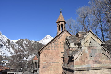Fototapeta premium Sunlit St John the Baptist Church with Mt Kazbek in Background, Stepantsminda, Georgia