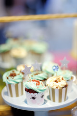 Delicious colorful wedding cupcakes with flower and stars and beautiful glazed cake.