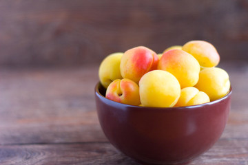 ripe fresh apricots in a bowl on a wooden table