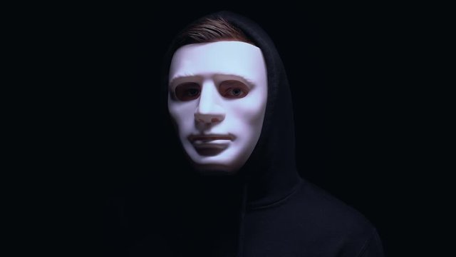 Frightening man in mask suddenly appearing from darkness, cyber attack, close-up