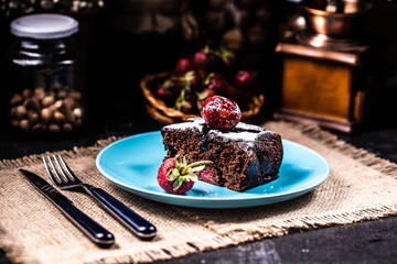 A slice of brownie with strawberries on a blue plate.