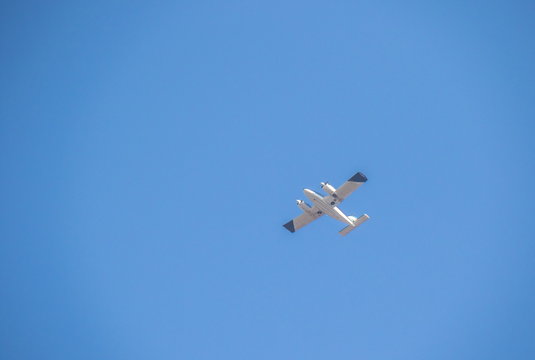 A small aircraft in flight isolated in a clear blue sky image with copy space in landscape format
