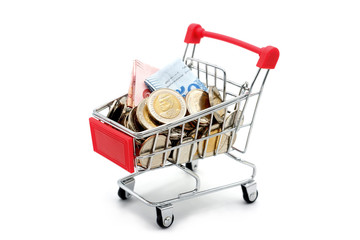 New Thai Baht banknotes and coins in red miniature shopping cart, isolated on white background. Business and finance concept.
