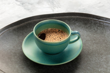 Black coffee in a teal cup on a tray with a place for text