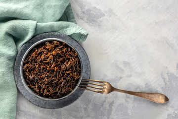 Wild black rice, shot from above with a fork and copy space, on teal and grey textures