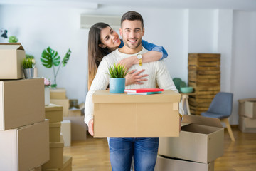 Beautiful young couple moving to a new house, smiling happy holding cardboard boxes at new apartment