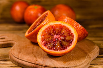 Cutting board with halved sicilian oranges on a wooden table