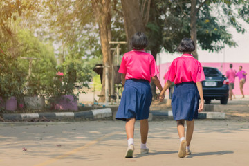 Back view of happiness primary girl students in pink shirt and blue skirt walk to classrooms with their friends.