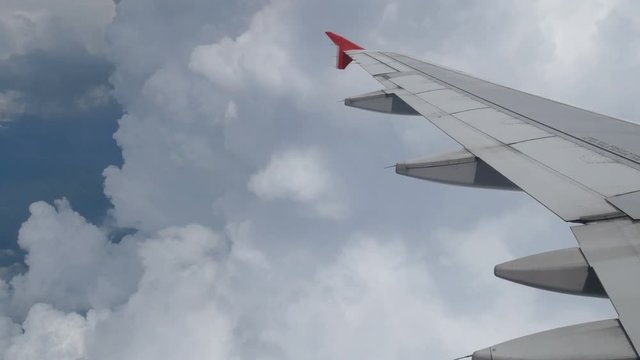 4K footage. traveling by air. aerial view through an airplane window. wing airplane flying in to the white clouds