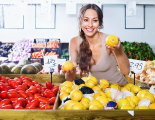 Obraz premium Positive young woman buying fresh lemons