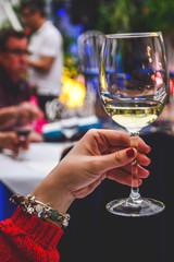 Woman hand holding wineglass with white wine toasting.