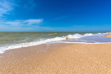 Fototapeta na wymiar sea wave foam sand gold color. close-up , blue sky