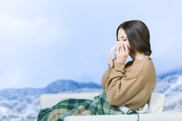 Brunette woman sneezing in a tissue in the living room