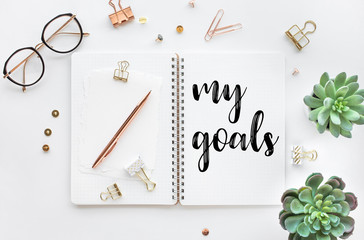 My goal concepts with text on notepad with accessories on white desk table background