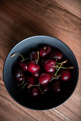 A bowl of cherries on a wooden table.