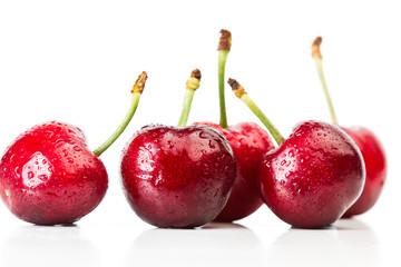 Cerezas frescas con gotas de agua sobre un fondo blanco aislado. Vista de frente y de cerca