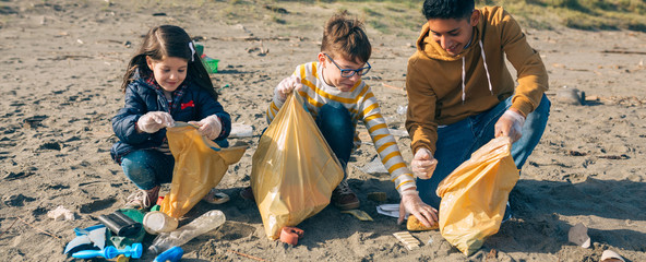 Group of young volunteers picking up trash on the beach
