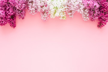 Fresh branches of white and purple lilac blossoms on pastel pink background. Empty place for...