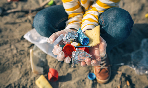 Detail of child hands with garbage collected from the beach - Powered by Adobe