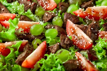 warm salad with chicken liver and grapes on a wooden table