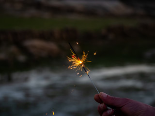 An unrecognizable person with a sparkler sizzling in his hand