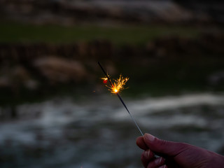 An unrecognizable person with a sparkler sizzling in his hand