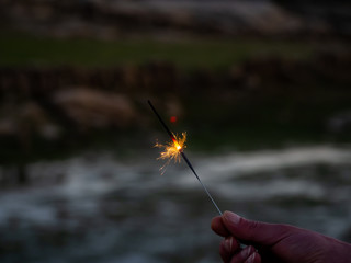 An unrecognizable person with a sparkler sizzling in his hand