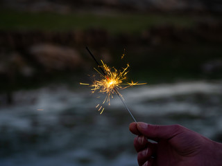 An unrecognizable person with a sparkler sizzling in his hand