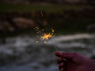 An unrecognizable person with a sparkler sizzling in his hand