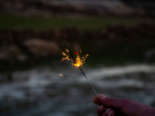 An unrecognizable person with a sparkler sizzling in his hand