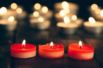 candles burning in darkness over black background. commemoration concept.