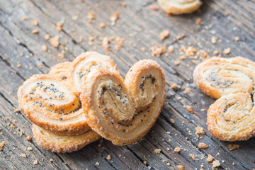 Sugar cookie curls with poppy seed puff pastry on wooden background. Confectionery for the recipe. Pastries, dessert