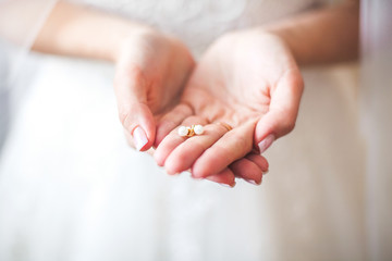 White earrings in hands of the bride