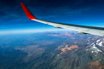 Fototapeta premium Wing of an airplane flying above the morning clouds and Andean mountain range