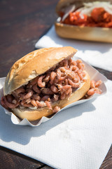 Fischbrötchen mit Nordseekrabben und Alaska Seelachs draußen auf Fischmarkt Holztisch als schneller regionaler Imbiss