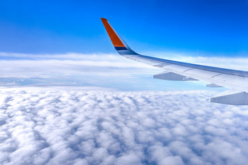 Fototapeta premium Bussiness and travel concept. Aerial view through window inside aircraft cabin with beautiful blue sky and cloud with sunlight, copy space, top view