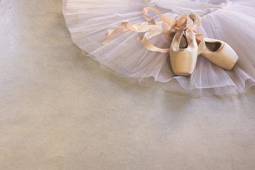 white tutu and pointe shoes on a grey concrete floor