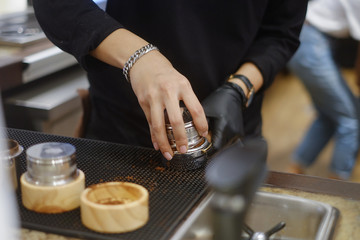 Barista tamping ground coffee for making hot esspresso coffee with espresso machine 
