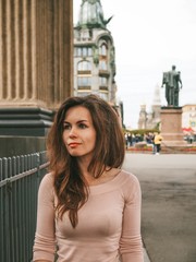 Brunette girl with long hair stands  on the streets in the center of St. Petersburg near the canals on the background of the Kazan Cathedral