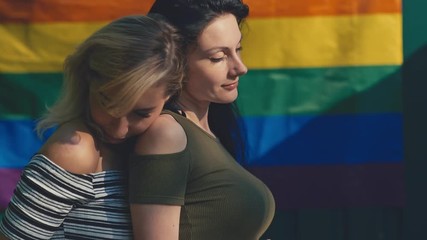 Young lesbian LGBT couple on a background of the rainbow flag. LGBT rights, lesbian family - Powered by Adobe