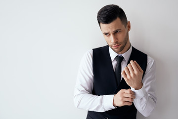 Handsome young man adjusting his sleeves and fixing his cufflinks against white background