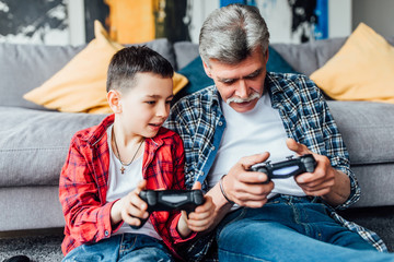Active inspired man and his grandson enjoying new video game..