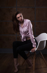 Test shoot of a pretty brunette girl posing in shirt at the chair