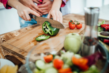 Close up photo. Hands  cutting an healthy fresh vegetarian salad in a bowl, fresh raw vegetables on background, top view.